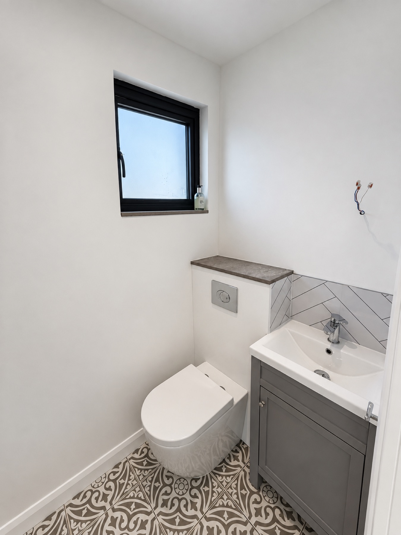 Finished garden room bathroom with WC, vanity, black framed window and patterned floor tiles