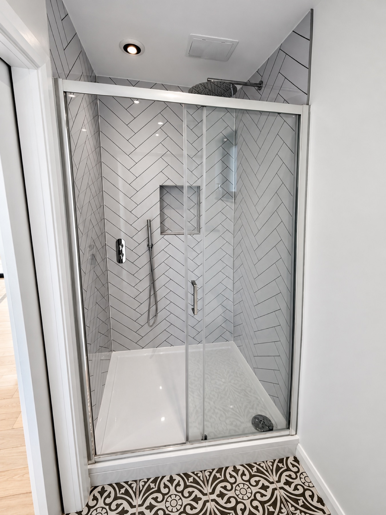 Enclosed shower with herringbone wall tiles inside the Maidenhead garden room bathroom